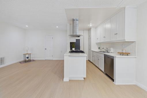 A kitchen with white cabinets and a wooden floor.