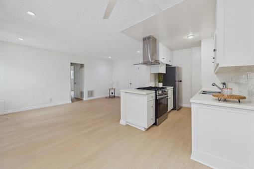 A kitchen with white cabinets and a wooden floor.