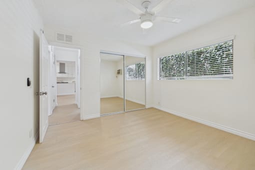 A room with a ceiling fan and sliding glass doors.
