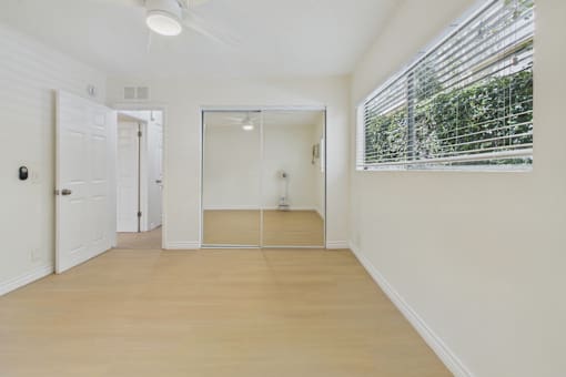 A room with a white door, a mirror, and a ceiling fan.