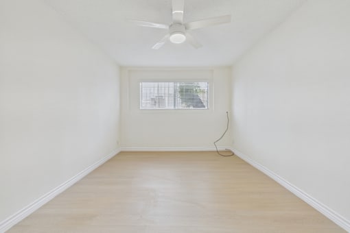 A room with a ceiling fan and a window with blinds.