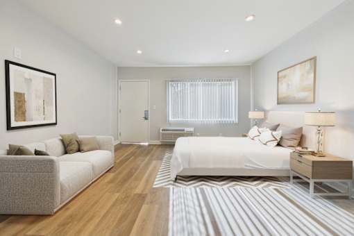 A well-lit bedroom with a large bed and a couch.