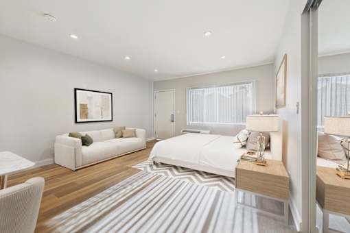 A bedroom with a bed, a couch, a chair, and a rug.