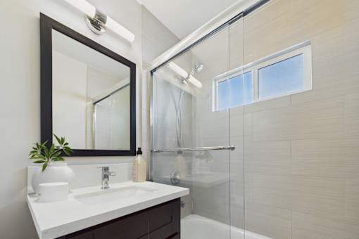 A bathroom with a sink, mirror, and shower.