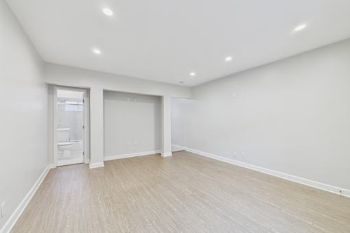 A large empty room with a doorway leading to a bathroom.