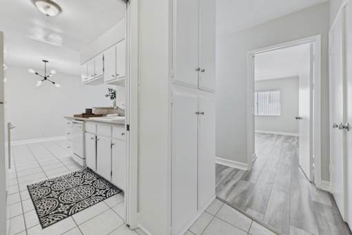 A kitchen with white cabinets and a black and white patterned rug.