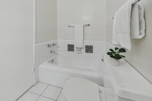 A white toilet sits next to a white bathtub in a bathroom.