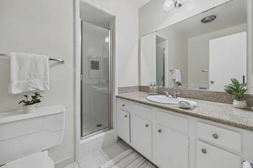 A white bathroom with a sink, mirror, and shower.