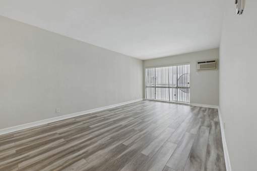 A room with wooden flooring and a window with blinds.