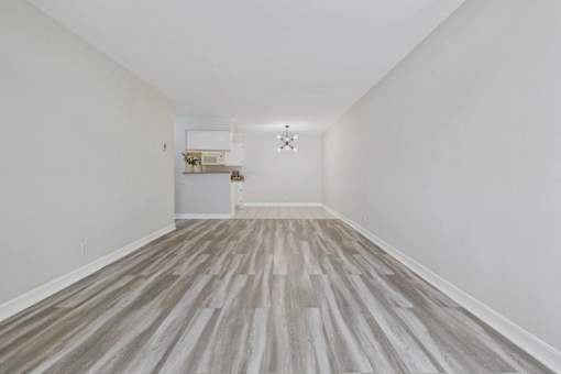 A long hallway with wood flooring and white walls.