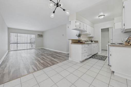 A spacious kitchen with white cabinets and a tiled floor.