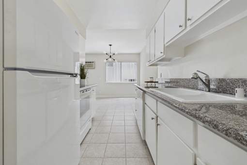 A kitchen with white appliances and granite countertops.