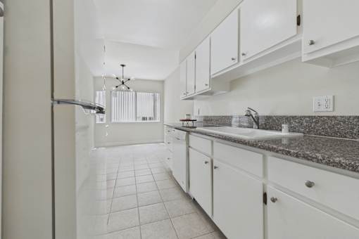A kitchen with white cabinets and granite countertops.