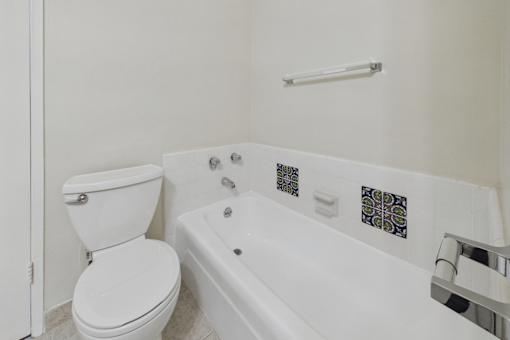 A white toilet sits next to a white bathtub in a bathroom.