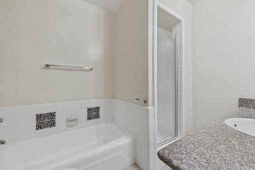 A white bathroom with a tub, sink and shower.