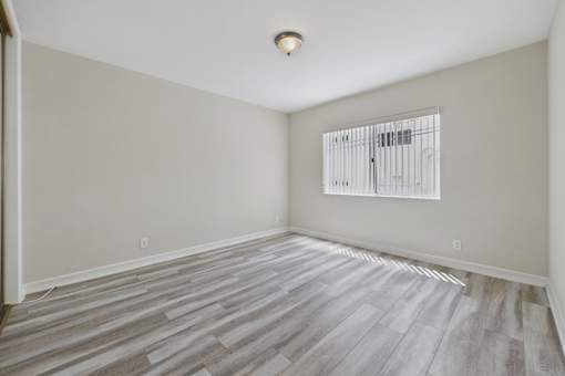 A room with wooden flooring and a window with blinds.
