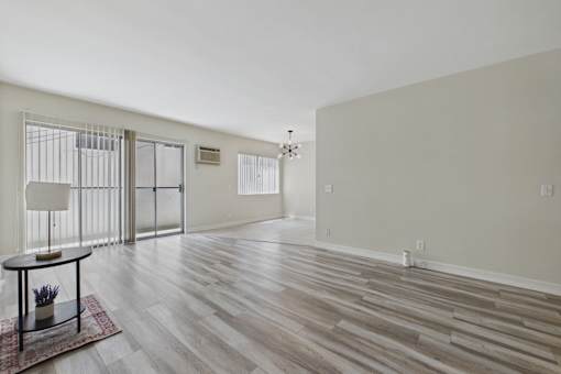 A room with wooden flooring and a table with a vase on it.