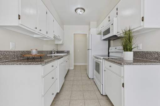 A kitchen with white cabinets and appliances.