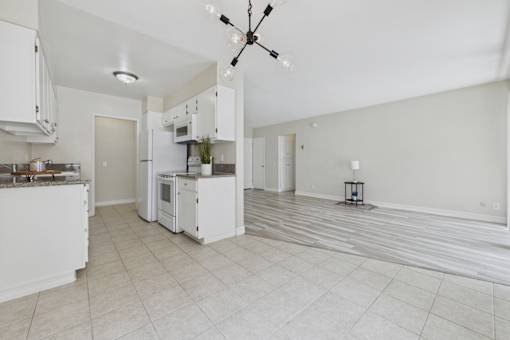 A kitchen with white appliances and a ceiling fan.