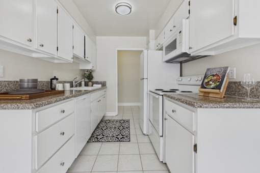 A kitchen with white cabinets and a granite countertop.