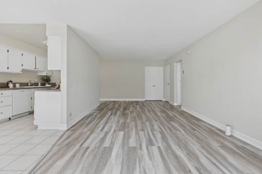 A kitchen with white cabinets and a wooden floor.