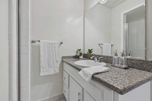 A bathroom with a granite countertop and white tiles.