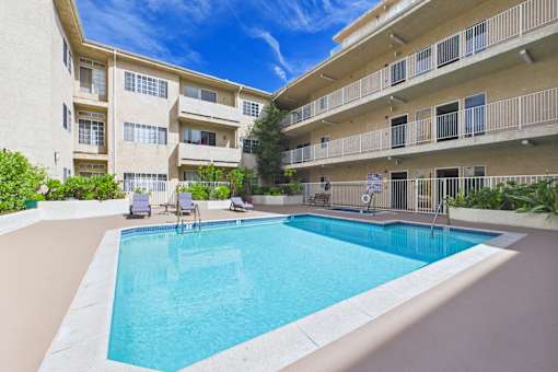 A swimming pool in front of a building with a blue sky in the background.