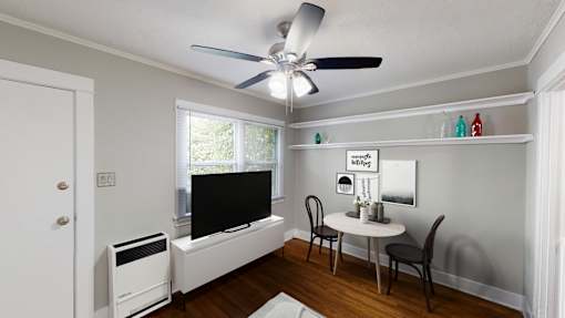 A room with a ceiling fan, a table with chairs, and a window.