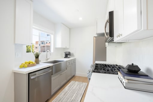 a white kitchen with stainless steel appliances and a window