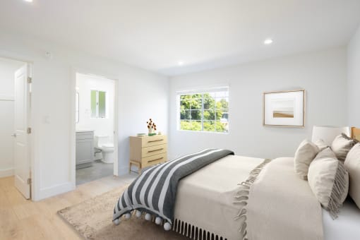 a white bedroom with a bed and a bathroom