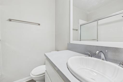 A white bathroom with a toilet, sink, and mirror.