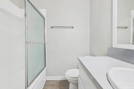 A white bathroom with a toilet, sink, and shower.