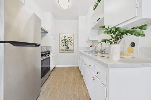 A kitchen with white cabinets and a stainless steel refrigerator.