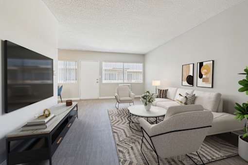 A living room with a grey couch, a white coffee table, and a television on the left side.