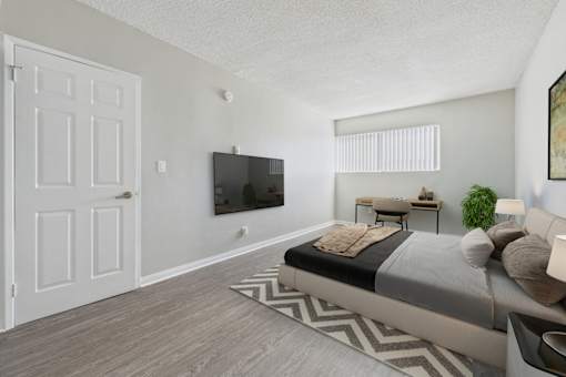 A bedroom with a large bed and a flat screen TV mounted on the wall.