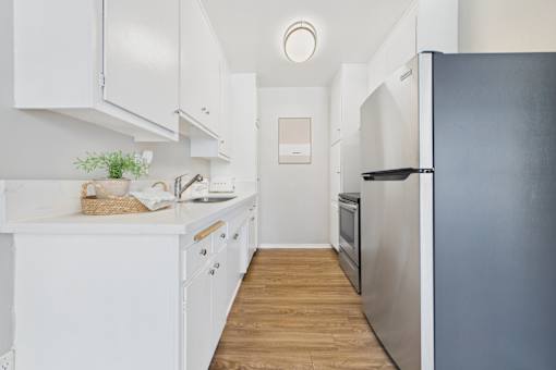 A kitchen with white cabinets and a black refrigerator.