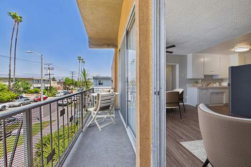 A balcony with a chair and a table overlooking a street.