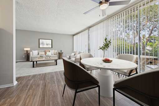 A living room with a white couch and a dining table with chairs.