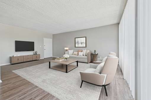 A modern living room with a grey sofa, a wooden coffee table, and a TV on the wall.