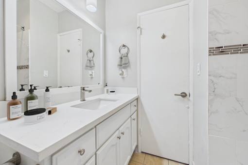 A white bathroom with a marble wall and a white sink.