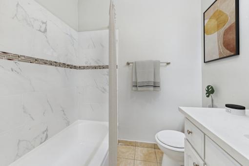 A bathroom with a marble wall and a white bathtub.
