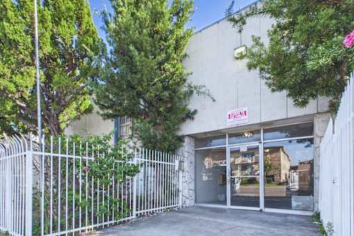 A white fence surrounds a building with a red sign that reads "EXIT".