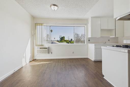 A kitchen with white cabinets and a window overlooking a street.