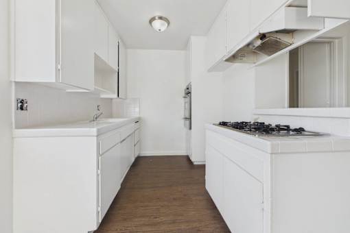 A white kitchen with wooden floors and white cabinets.