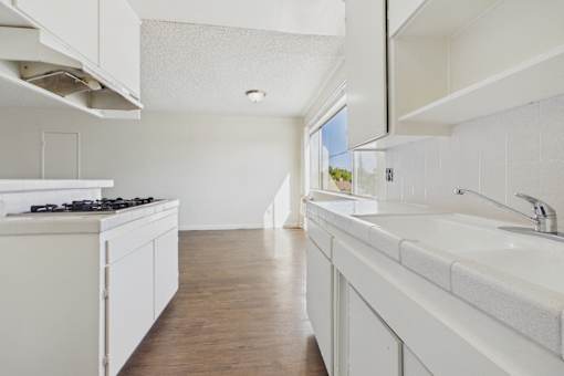 A white kitchen with wooden floors and a window.