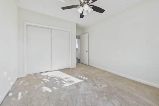A room with a ceiling fan and two white doors.