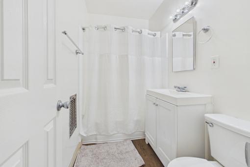 A white bathroom with a toilet, sink, and shower.
