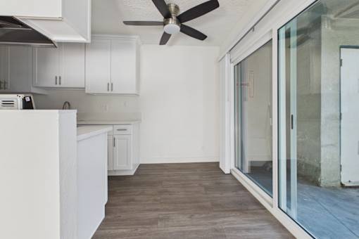 A modern kitchen with white cabinets and a ceiling fan.