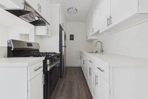 A modern kitchen with white cabinets and a black stove top oven.
