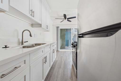 A modern kitchen with white cabinets and a wooden floor.